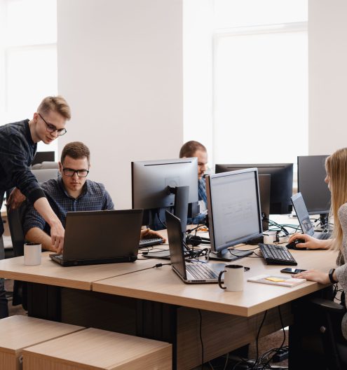 Full concentration at work. Group of young business people working and communicating while sitting at the office desk together with colleagues sitting in the background